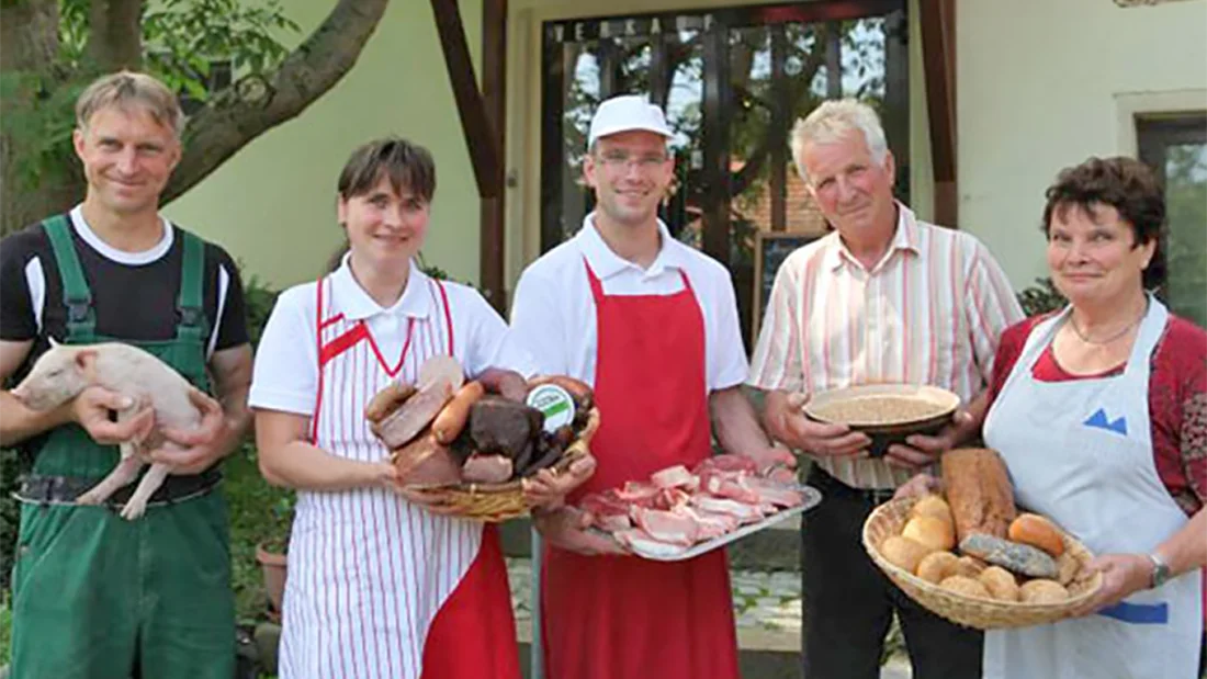 Team der Biofleischerei Mörl mit Wurstwaren und einem Brotkorb auf dem Arm