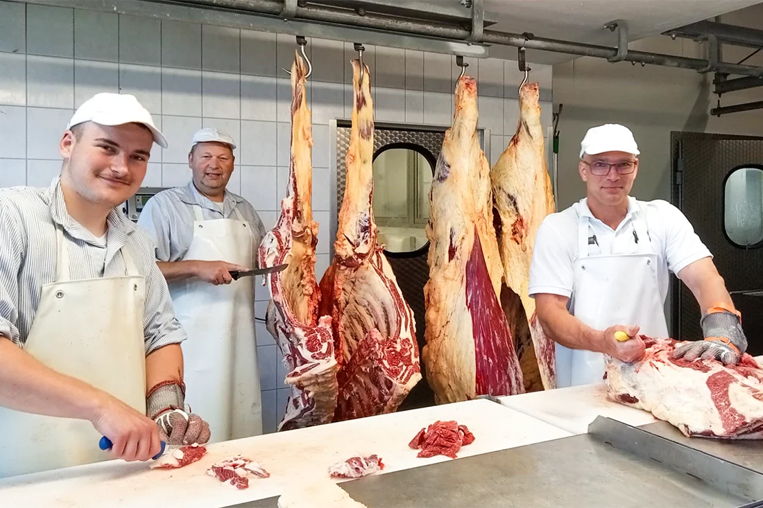 Drei Mitarbeiter der Bio-Fleischerei Mörl zerteilen Fleisch