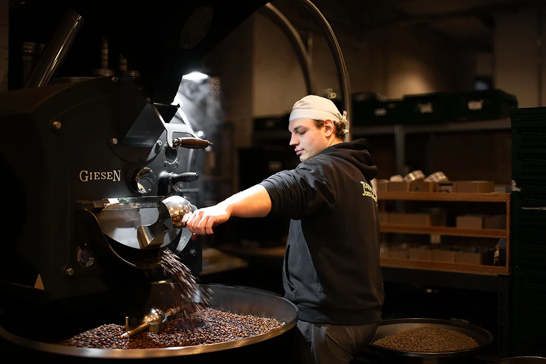 Mitarbeiter von Café Chavalo lässt Kaffeebohnen aus einer Röstmaschine laufen