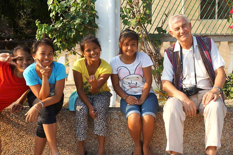 Mehrere Personen sitzen auf einer Mauer und lächeln in die Kamera