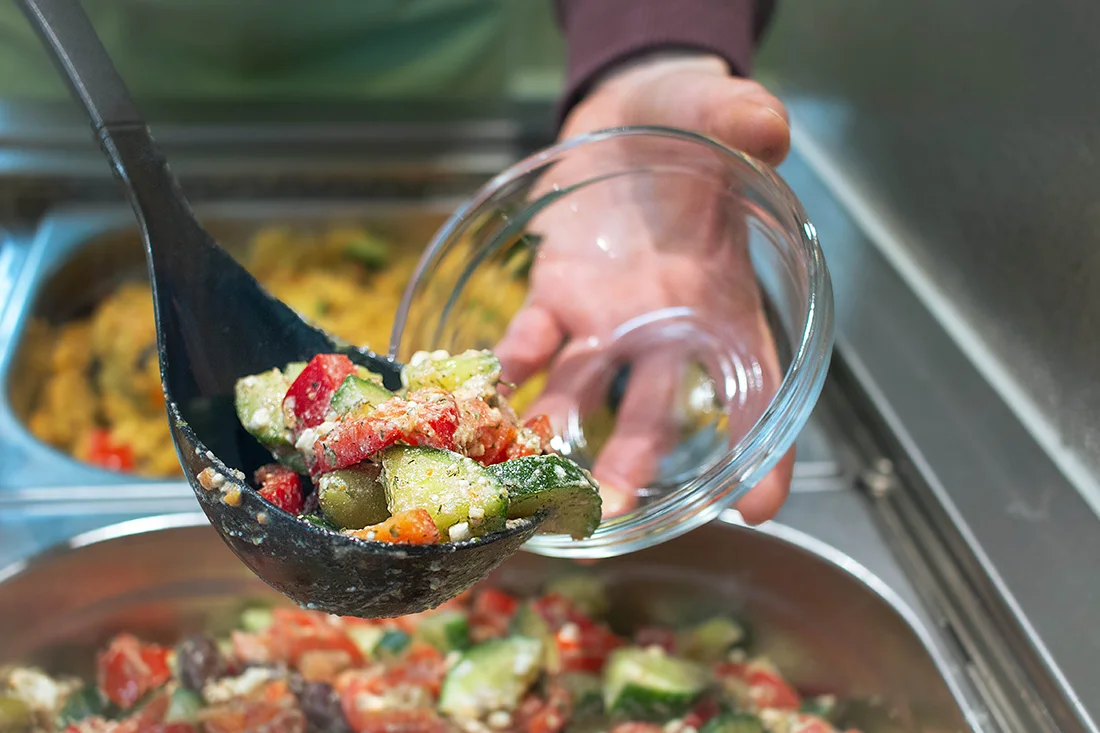 Salat wird in eine Schüssel gefüllt