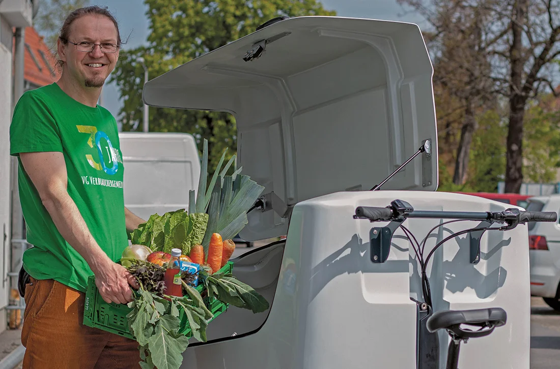 Mitarbeiter des BIOVELO Lieferdienst stellt eine Kiste Bio-Lebensmittel in das Lieferfahrrad