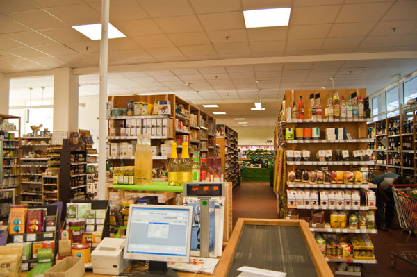 Kassenbereich und Blick durch Holzregale in die Gemüseabteilung des VG-Biomarktes in der Pohlandpassage